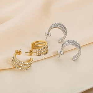 Macro shot of gold and silver C-shaped wheat earrings with rows of sparkling zircon stones