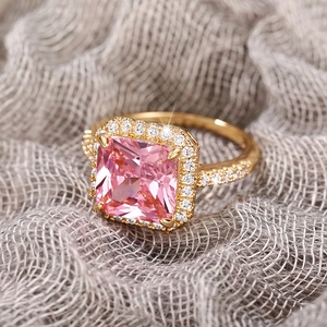 Macro shot of gold square pink gemstone ring with clear crystal halo and side accents