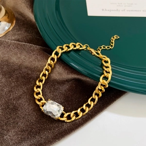 Macro detail of gold chunky Cuban chain bracelet with emerald green zircon gemstone