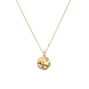 Macro detail of golden ball pendant with white heart motif on a thin metal chain necklace
