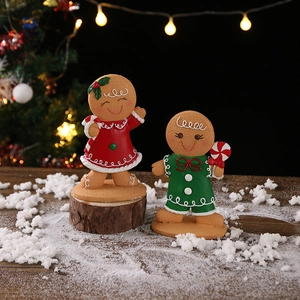 Set of two Christmas gingerbread man figurines with candy canes on snowy wood base