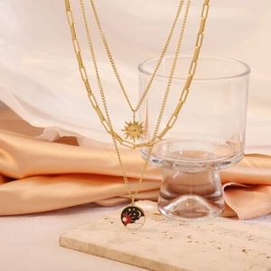 Three-layer gold necklace with sun pendant, paperclip chain, and star-moon enamel charm