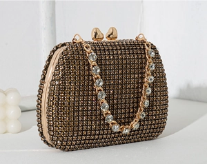 Detail of brown rhinestone evening clutch with gold metal frame and crystal heart clasp