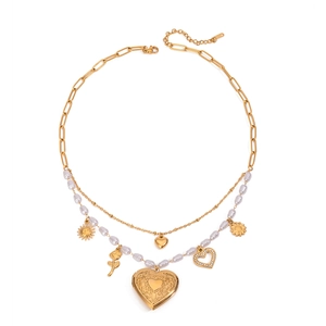Dettaglio di collana dorata a strati con perle e ciondoli a forma di cuore e rosa