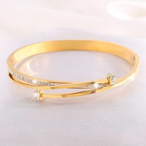 Close-up of gold-plated stainless steel bangle featuring double-layer crisscross design with crystals