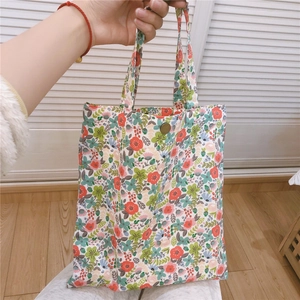 Gros plan détaillé d'un mini sac en toile à fleurs avec un bouton pression bronze