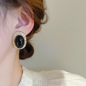 Close-up of vintage oval black stud earring with sparkling crystals on a model