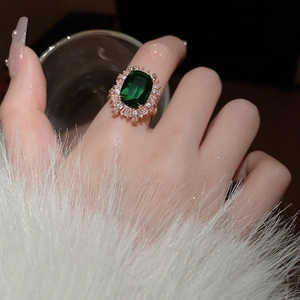 Detail of luxury emerald cut ring with halo setting on finger in premium lighting