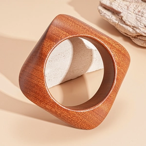 Macro detail of dark brown wood grain texture on geometric square-shaped cuff bracelet