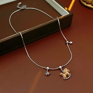 Détail d'un collier argenté avec pendentifs cheval en bois et clochette