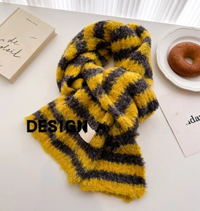 Detail shot of yellow and grey striped knit scarf with soft mohair texture on white desk