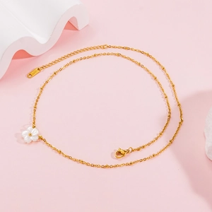 Elegant gold stainless steel necklace with a white shell flower pendant on pink background