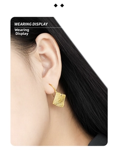 Close-up of golden geometric square earrings with vintage lava texture on model