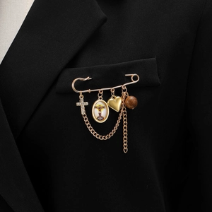 Détail d'une broche vintage dorée avec croix et pendentifs sur veste noire