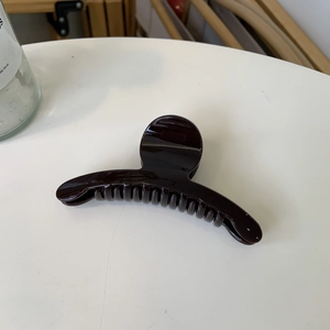 Detailed view of large dark brown acetate hair claw clip with glossy polished finish