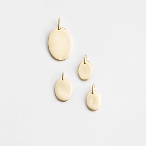 Detailed macro view of four various sized golden oval metal charms with hanging rings