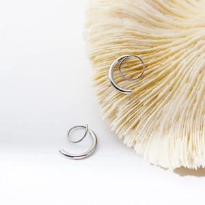 Detail of silver spiral twisted earrings on a white coral texture background