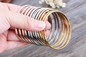 Detailed view of stacked polished titanium steel bangles in gold, silver, and rose gold