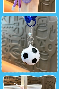Detail view of soccer ball keychain with silver metal clip and blue ring on bag