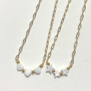 Gold paperclip chain necklace featuring three white heart and star shell pendants