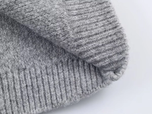 Macro detail of grey knit cardigan showing thick ribbed texture and wool blend fabric