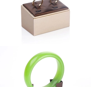 Detail showing gold jewelry boxes with brushed texture and a green jade bangle on a stand