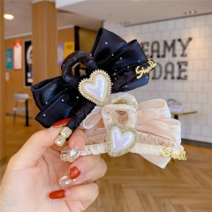 Detail of satin bow hair clips featuring heart-shaped pearls and gold Smile accents