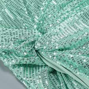 Macro shot of mint green sequins and mesh fabric on a sexy slit party dress