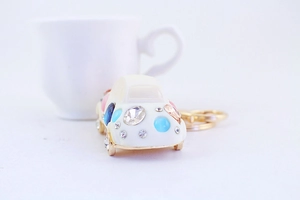 Close-up of golden car keychain encrusted with sparkling blue and pink rhinestones