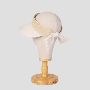 Dettaglio del cappello da sole color crema con trama intrecciata e fiocco decorativo