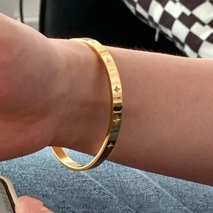 Detailed view of gold plated titanium steel bangle with engraved star patterns on wrist