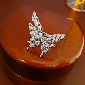 Macro shot of silver butterfly ring with pearl and cubic zirconia on dark wood
