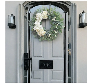 Detail of a decorative wreath with white roses and eucalyptus hanging on a blue door