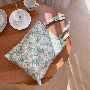Détail du sac cabas en coton fleuri sur table en bois avec tasse céramique
