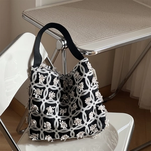 Detailaufnahme der geometrischen Stickerei und des Logo-Etiketts einer schwarzen Canvas-Tasche