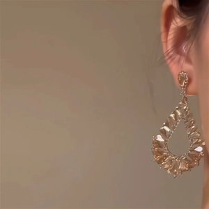 Gros plan de boucles d'oreilles goutte dorées avec cristaux sur le mannequin