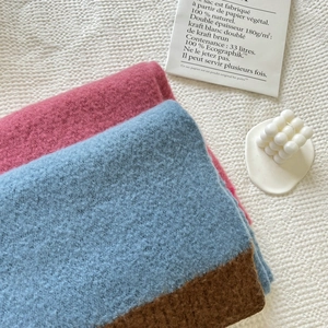 Close-up of soft knit scarf with pink blue and brown color block texture on white knit