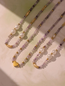 Detail of beaded necklaces with purple stones, white pearls and gold heart pendant