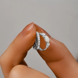 Close-up of S925 silver hoop earring with opal and zircon stones held by fingers