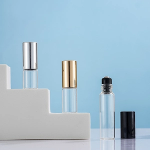 Detailed view of glass roller bottles with metallic silver gold and black caps on white stand