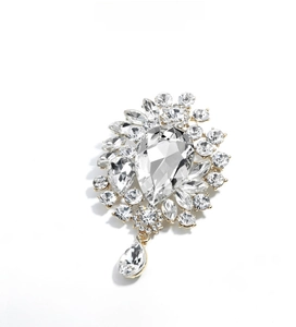Macro detail of luxury crystal brooch with teardrop pendant in sparkling gold finish