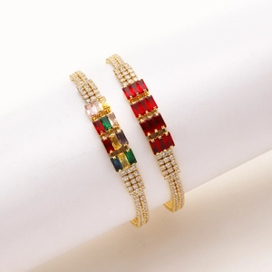 Dettaglio di bracciali dorati con zirconi colorati rettangolari e file di pavé di diamanti