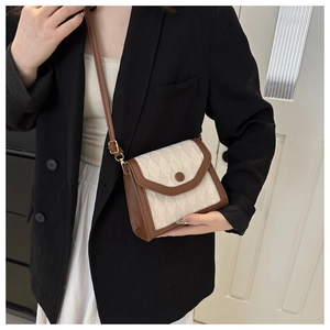 Detail of quilted crossbody bag in beige and brown leather showing shoulder strap fit