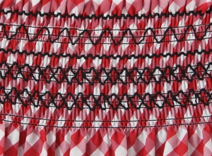Gros plan sur le tissu à carreaux rouge et blanc avec détails de smocks élastiques noirs