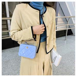 Detail view of blue jelly crossbody bag with quilted pattern and gold flower buckle