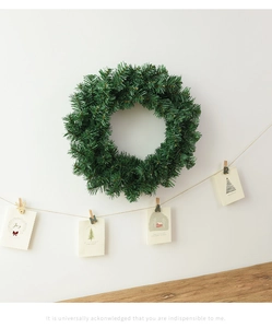 Détail d'une couronne de Noël verte sur mur blanc avec carte décorative joyeux Noël