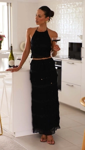 Detail of elegant black halter top and layered chiffon maxi skirt on a model