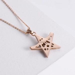 Punk style rose gold pentagram star pendant necklace on a grey stone background
