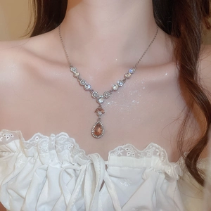 Detail einer eleganten Silberkette mit bernsteinfarbenem Tropfen und Diamantakzenten
