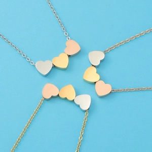 Three-heart pendant necklaces in gold, rose gold, and silver finishes on blue background